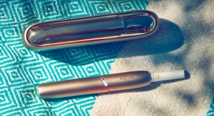 Golden IQOS and its cover kept on a blue cloth