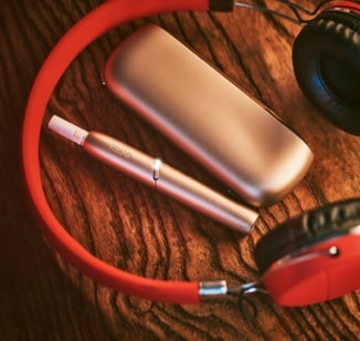 An IQOS  device next to red headphones.