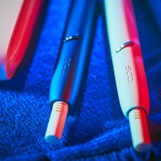 A blue and a white IQOS device on a blue surface.