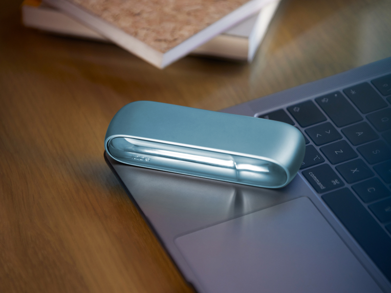 Turquoise IQOS Originals Duo device on a laptop. 