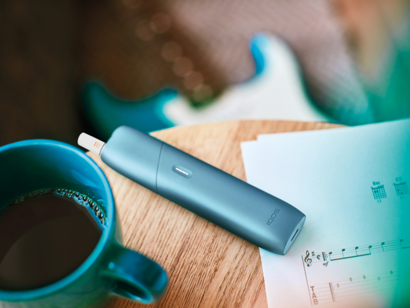 Turquoise IQOS Originals One device on a coffee table.