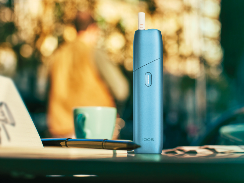 Turquoise IQOS Originals One device on a coffee table.