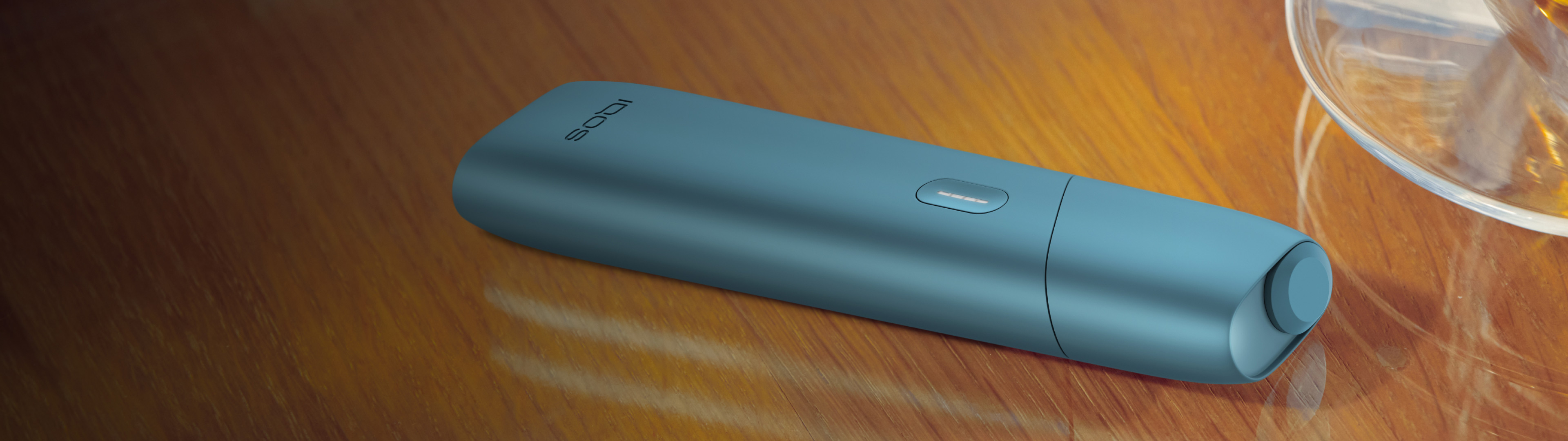 Turquoise IQOS Originals One device on a wooden table.