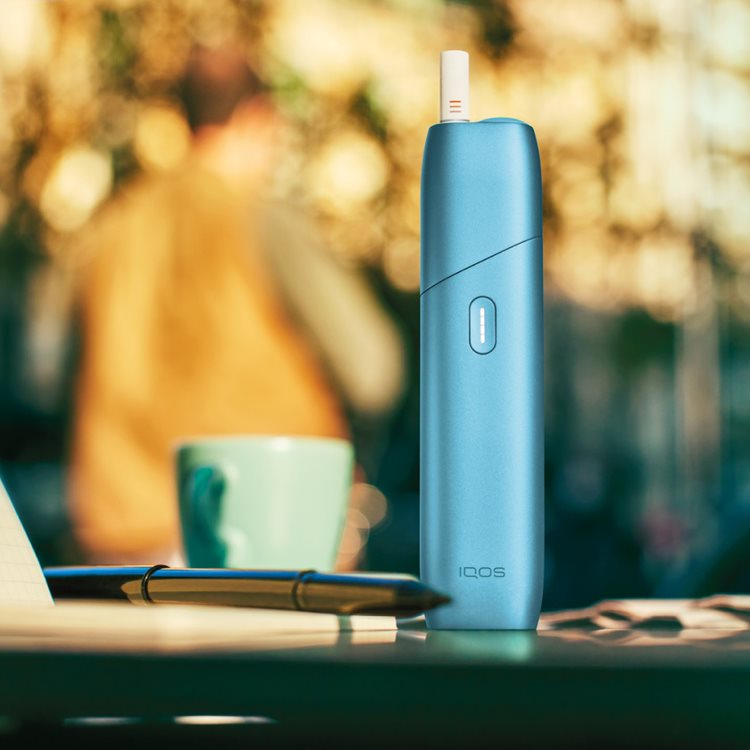 Turquoise IQOS Originals One device on a coffee table.