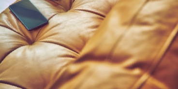 A smartphone on a leather sofa cushion.