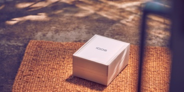 An unopened IQOS device box on a rug.