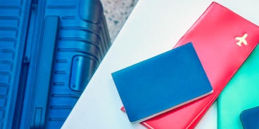 A passport, plane ticket, and IQOS device on a desk.