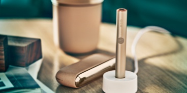 A charging Pebble Beige IQOS ILUMA device.