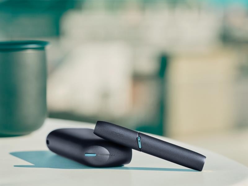 IQOS Originals Duo Holder and Pocket Charger in black color on a coffee table